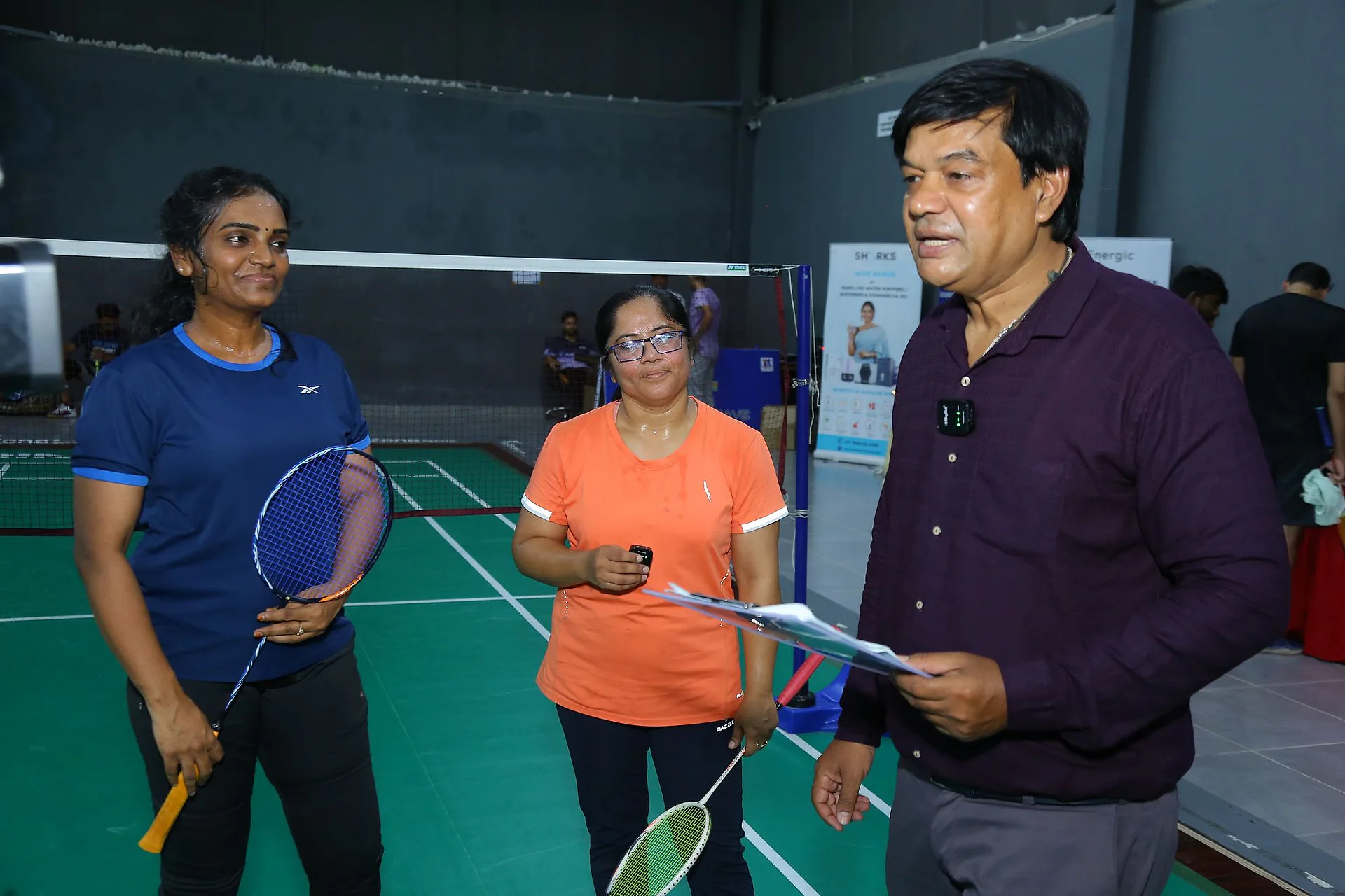 Players and an official talking on the green badminton court at the Doctors Badminton Championship