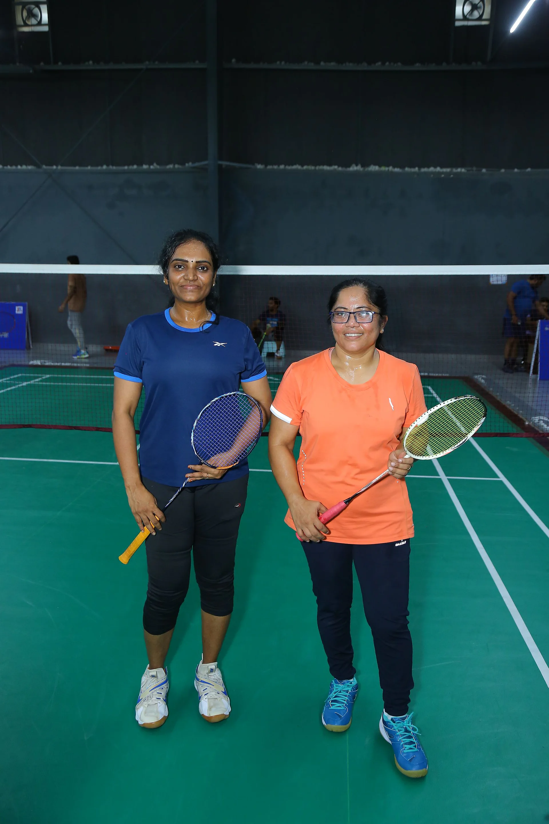 Two doctors posing with rackets on the green court