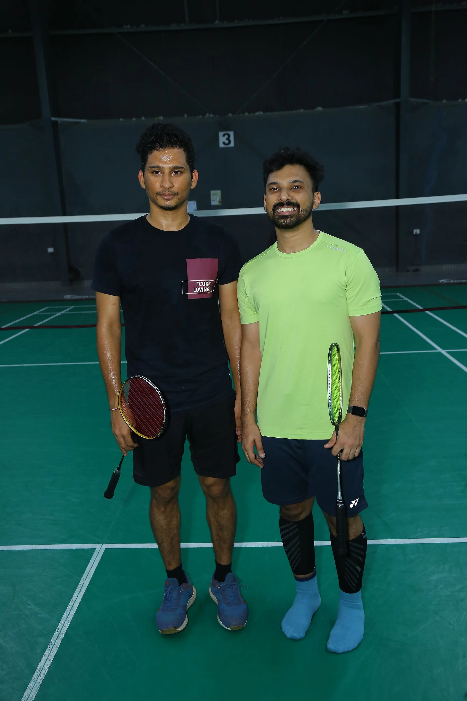Two players standing with their rackets on the badminton court