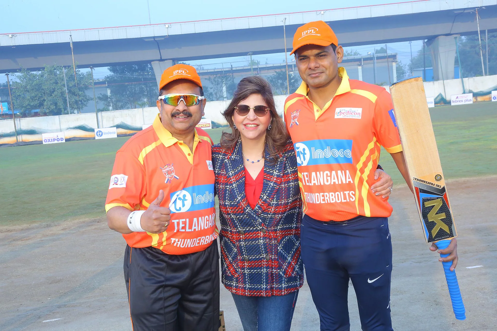 Two players and a guest posing together with a cricket bat at the IPPL