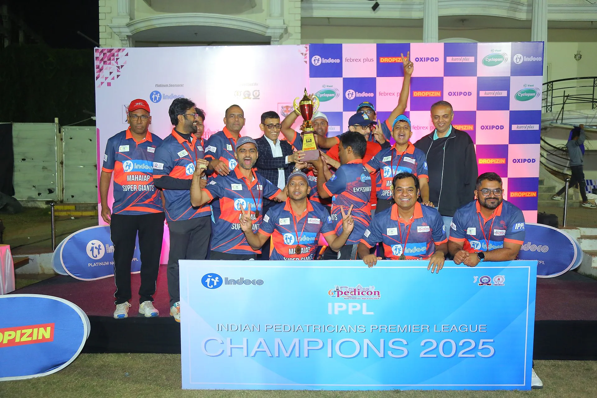 A team and officials posing with the trophy behind the IPPL banner
