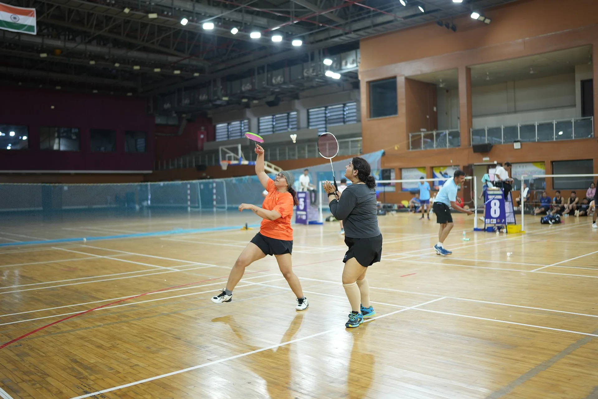 A doubles pair mid-rally on the indoor court