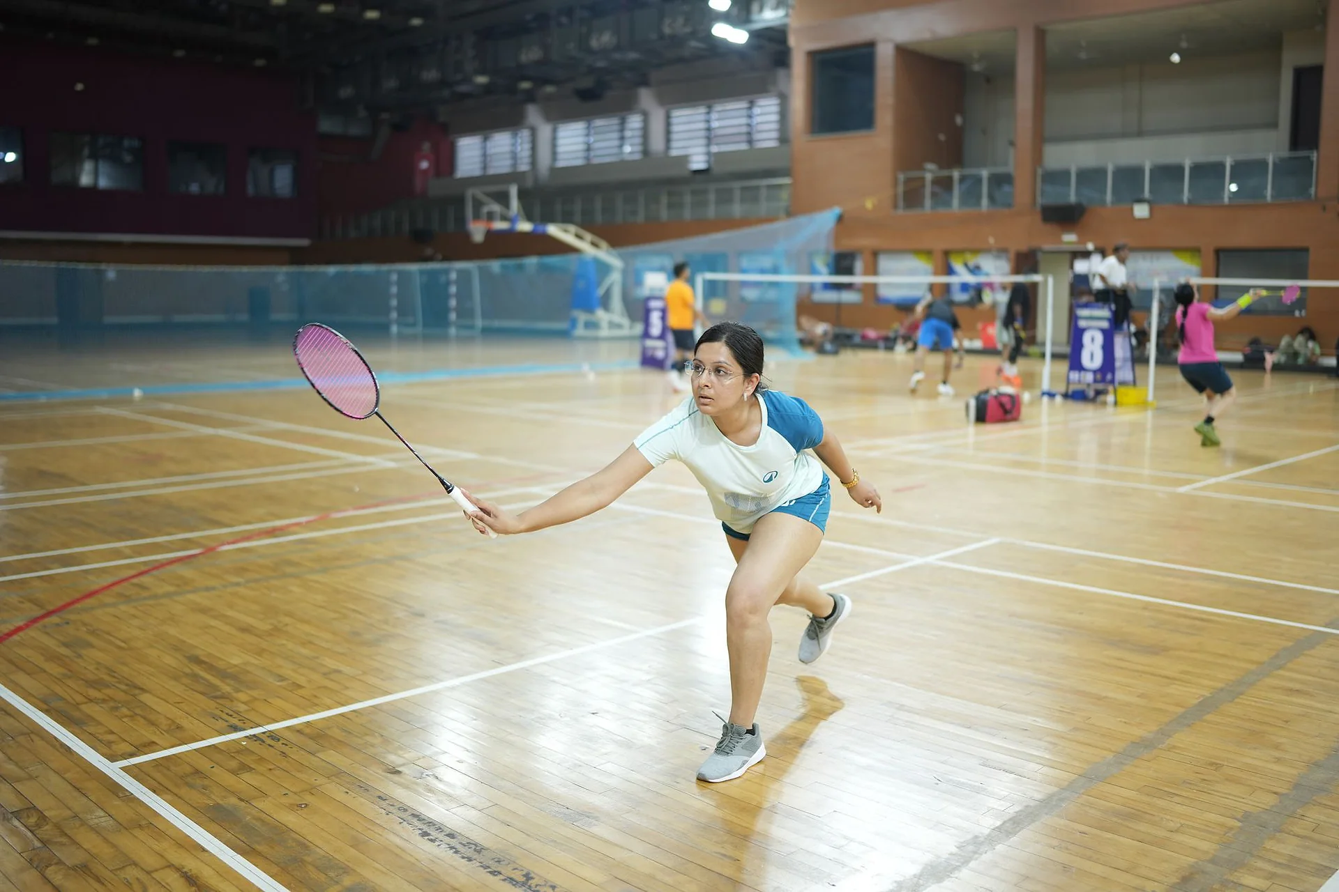 A player in a white top lunging forward in a rally